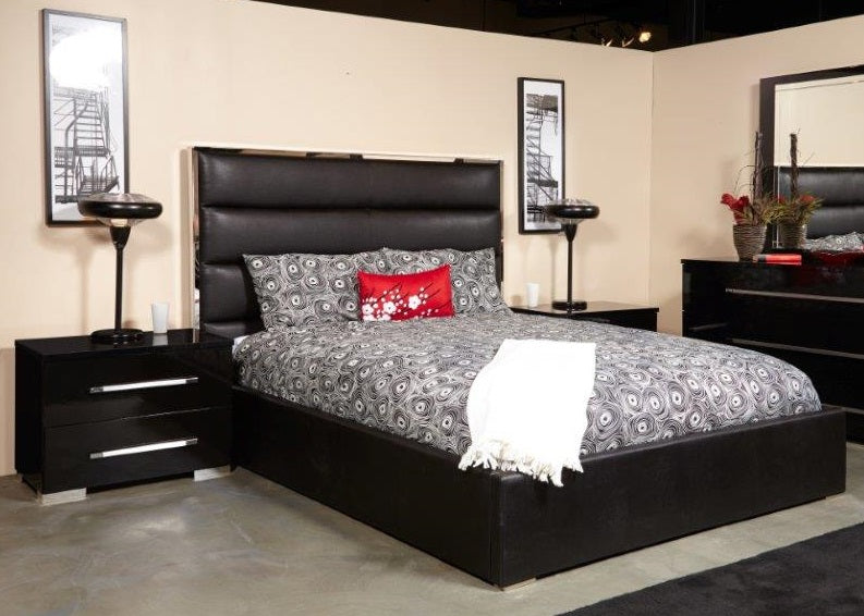 A black metal bed with pedestals and a high headboard, dressed with bedding.