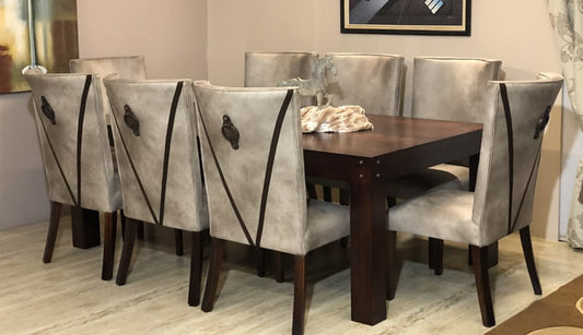 A dining set including a wooden table and six chairs with upholstered seats, arranged in a room with a window and decorative curtains.